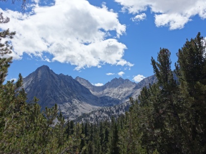 A huge bowl and jagged peaks with specks of snow pack in the distance.