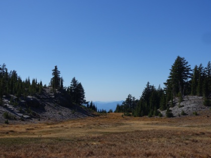 Pumice plain mixed with meadow fading off into the distant hazy mountain ranges.