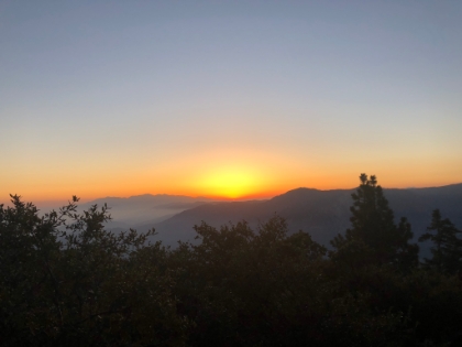 The very last slice of the sun as it sets behind the mountains.