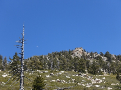 The rising moon alongside a prominent rock formation.