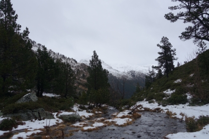 Looking back at the creek spilling over the edge into the valley below. The snow is starting to get thick along the trail. There's still a light rain and the temperature is just above freezing.