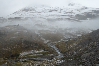 A good sized stream winding through the valley admidst the snow and increasingly heavy rain.