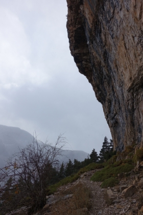 The trail winding under an overhanging cliff. Injuries from falling rock are evidently pretty common here. There's a near constant drip of water onto the trail falling from the cliff above.