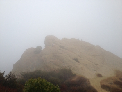 A few hikers sitting on Eagle Rock in the fog.