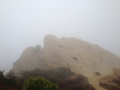 A few hikers sitting on Eagle Rock in the fog.